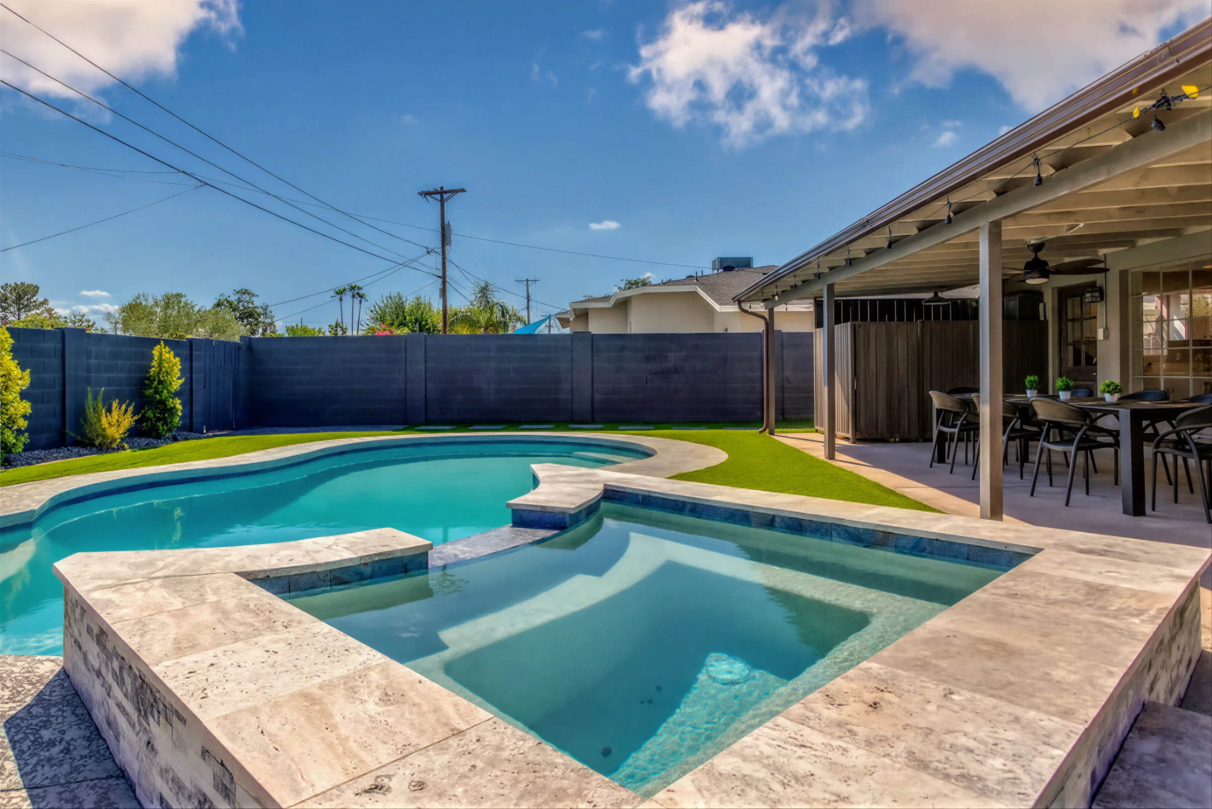 Filled pool and raised spa with travertine deck in daylight