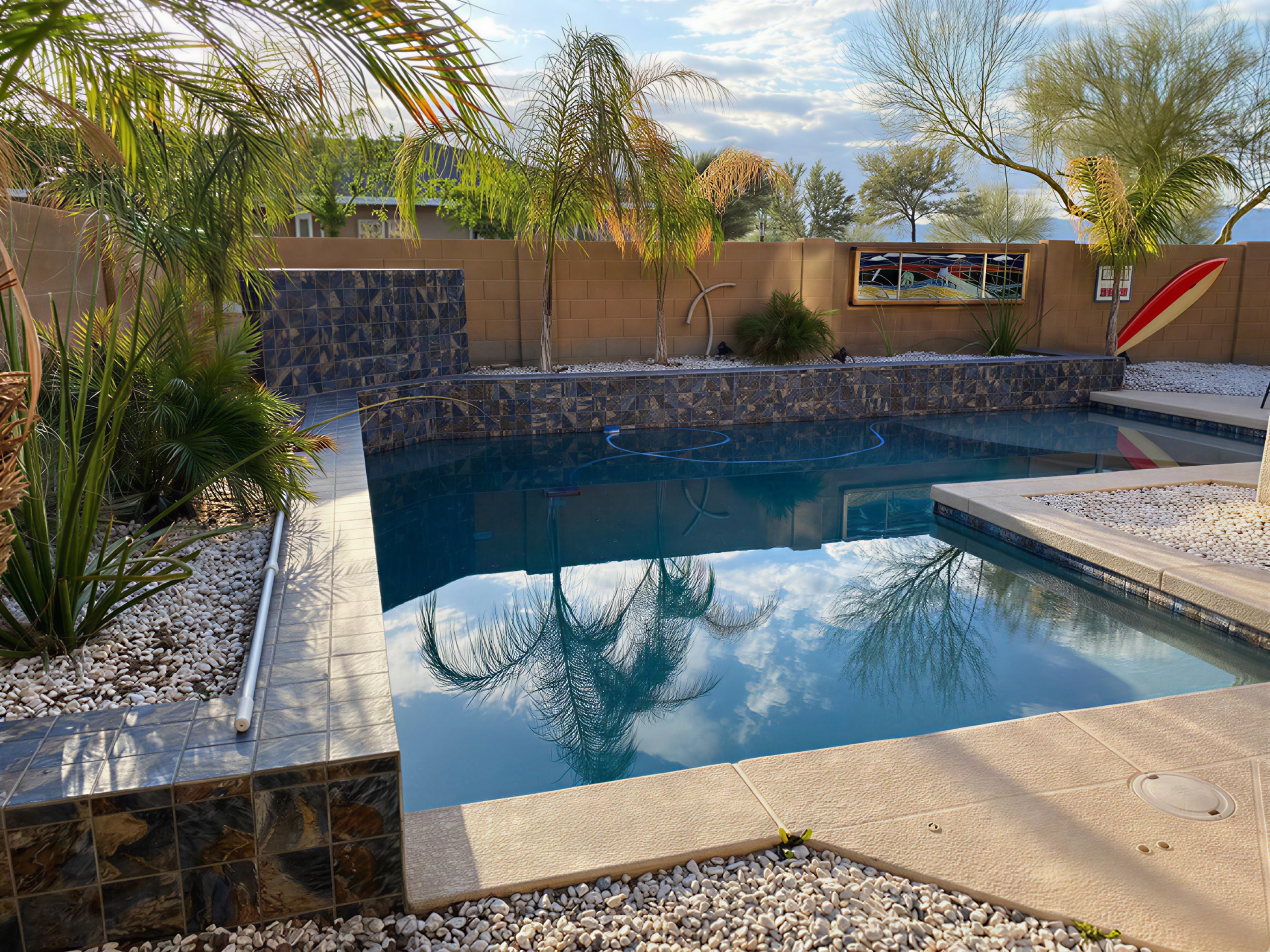 Completed courtyard pool restoration with dark blue water and desert landscaping
